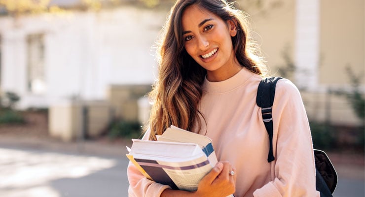 Community college student carrying her books to class.