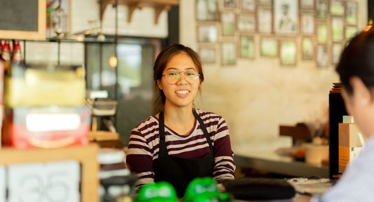 Female student working part time at a cafe to improve her college cash flow.