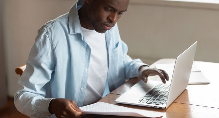 Male student analyzing his expenses on his laptop in order to improve his college cash flow.