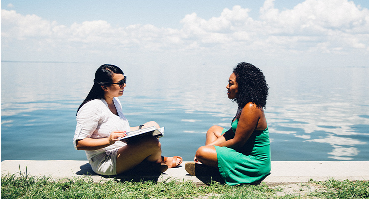 Two college students sitting together by the water.