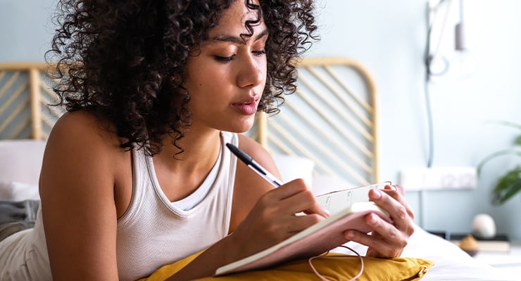 A college student journaling in bed.