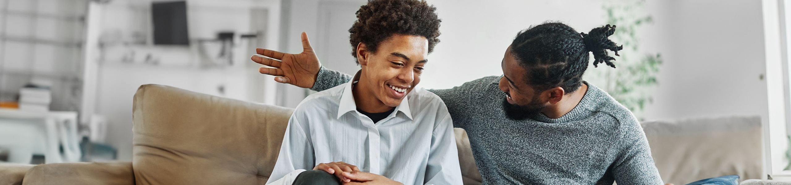 Two smiling men sitting on a couch.