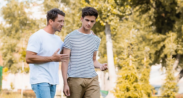 A father talking to his son outdoors.