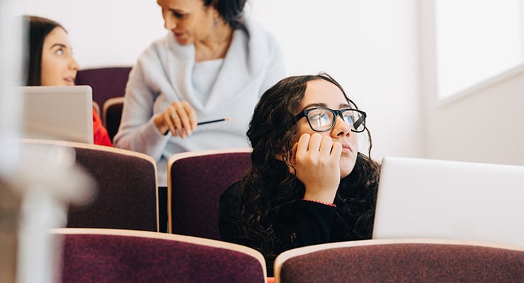 Female student wearing glasses sitting in class.