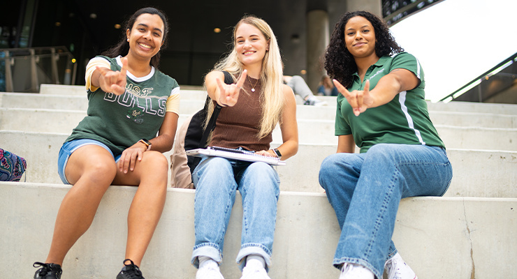 Three USF students holding up the bulls sign.