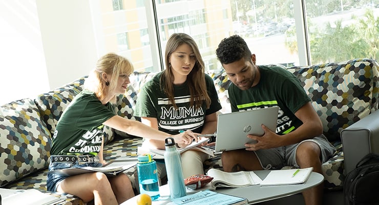 Three USF students sitting on a couch and working on a project.