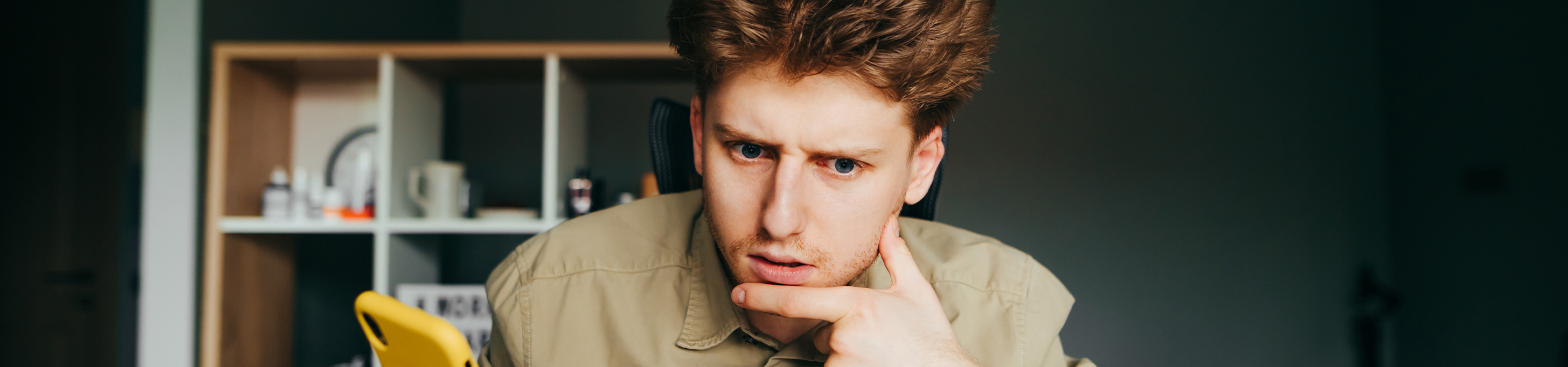 A guy holding his phone while doing some research on scholarship scams.