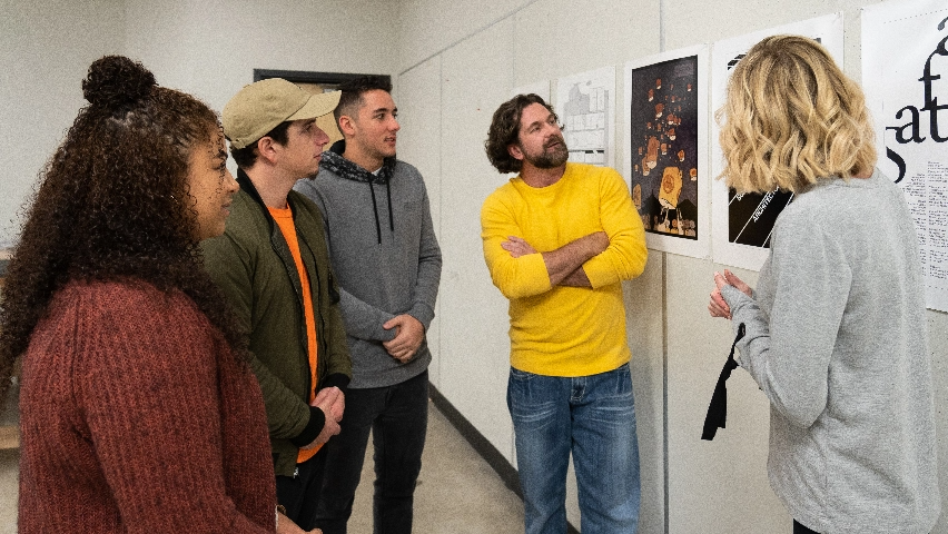 A group of people looking at art on the wall.