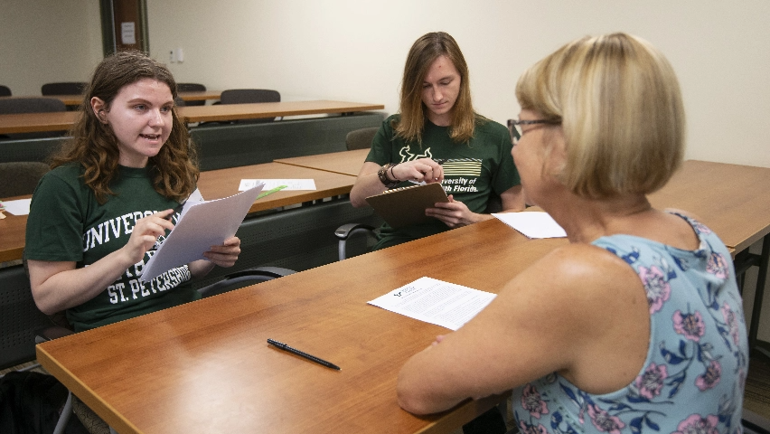 Two students and their professor having a discussion in a classroom.