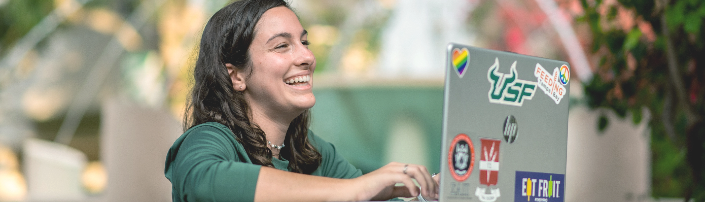 A USF student smiling and using her laptop.