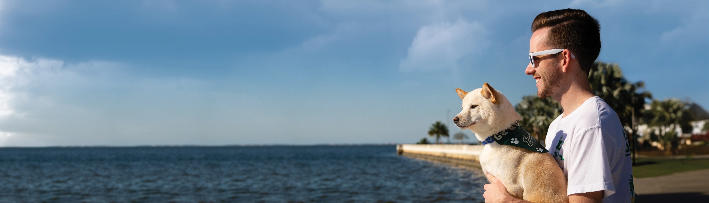 A USF student holding his dog by the water in Tampa Bay.