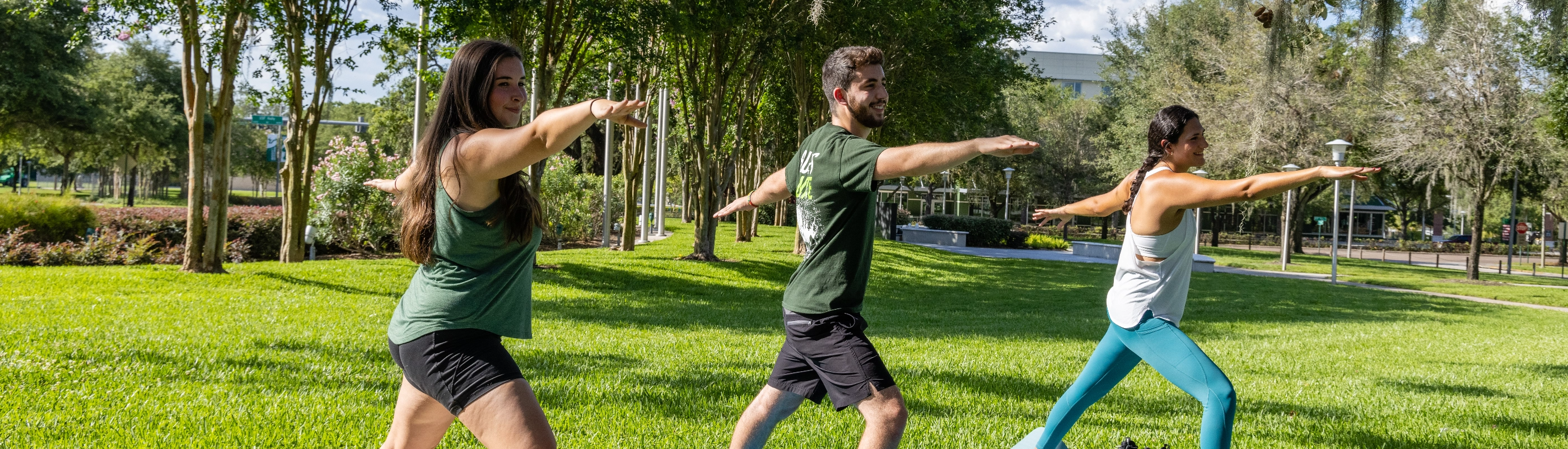 Three USF students doing yoga on campus.