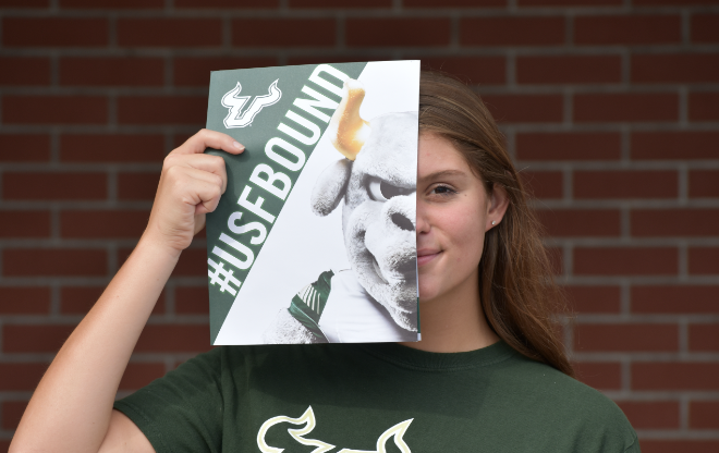 Female student holding up a USF bound sign.