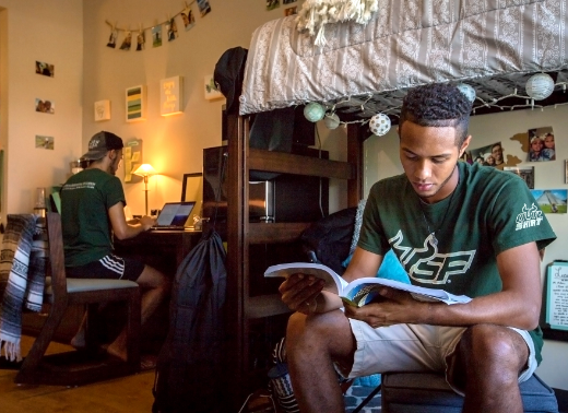 Two male USF students sitting in their USF Tampa apartment on campus studying.